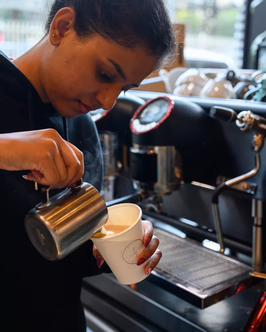 Barista pouring a takeaway coffee