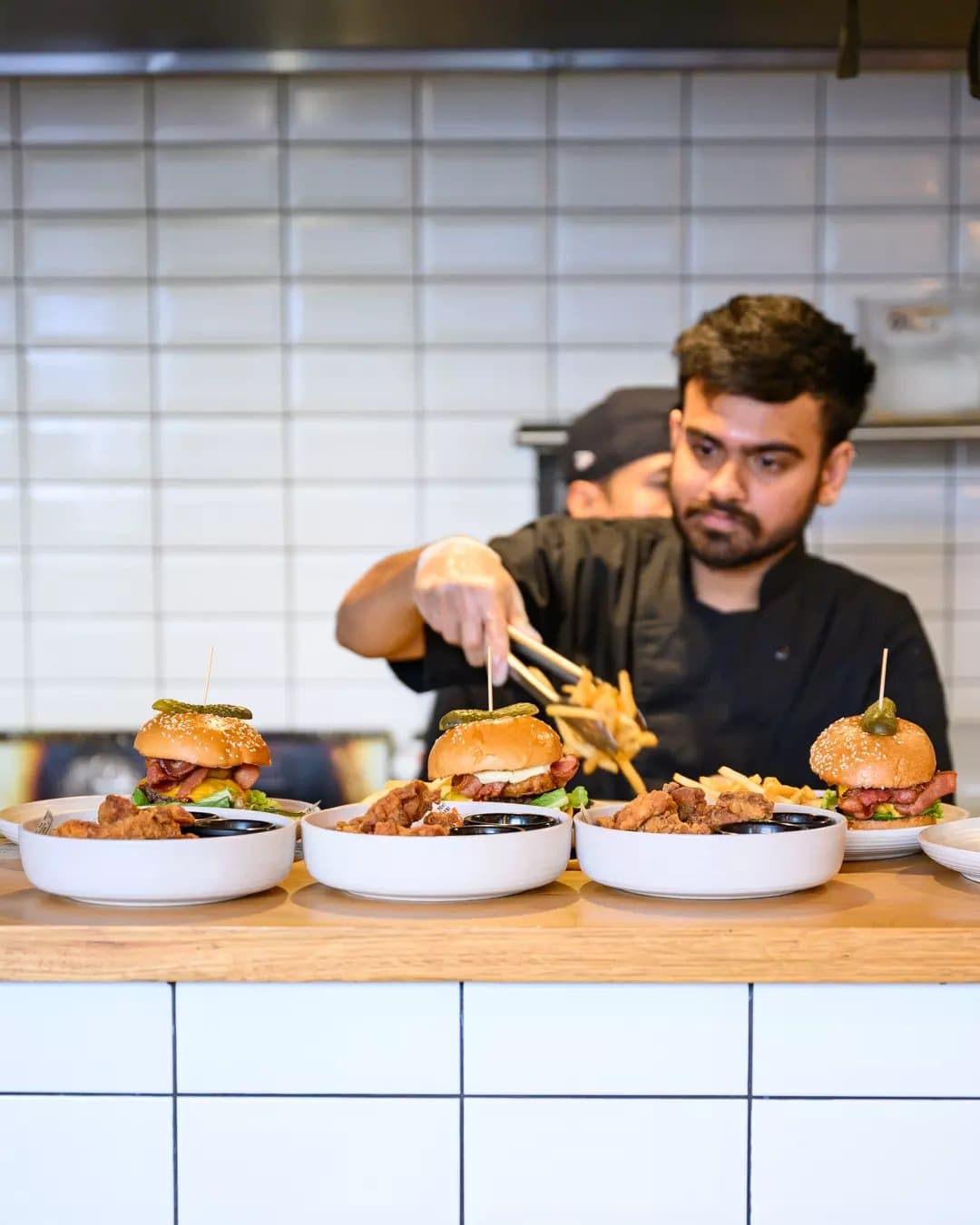 Chef finishing a row of burgers